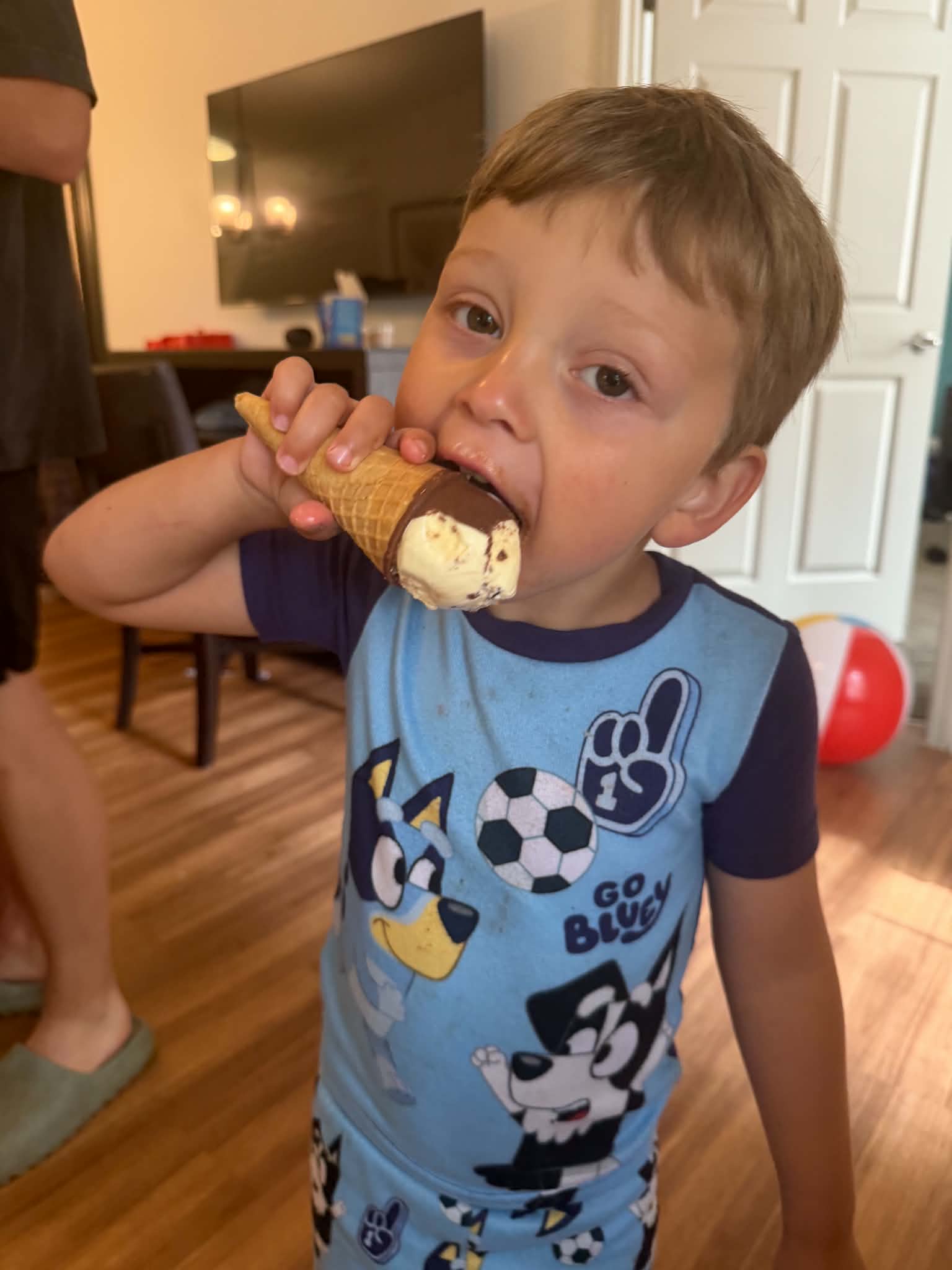 A young boy eating a chocolate-dipped ice cream cone inside the resort room