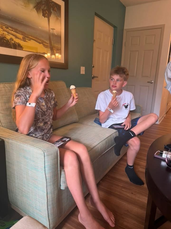 Two children relax on the resort room couch eating ice cream cones