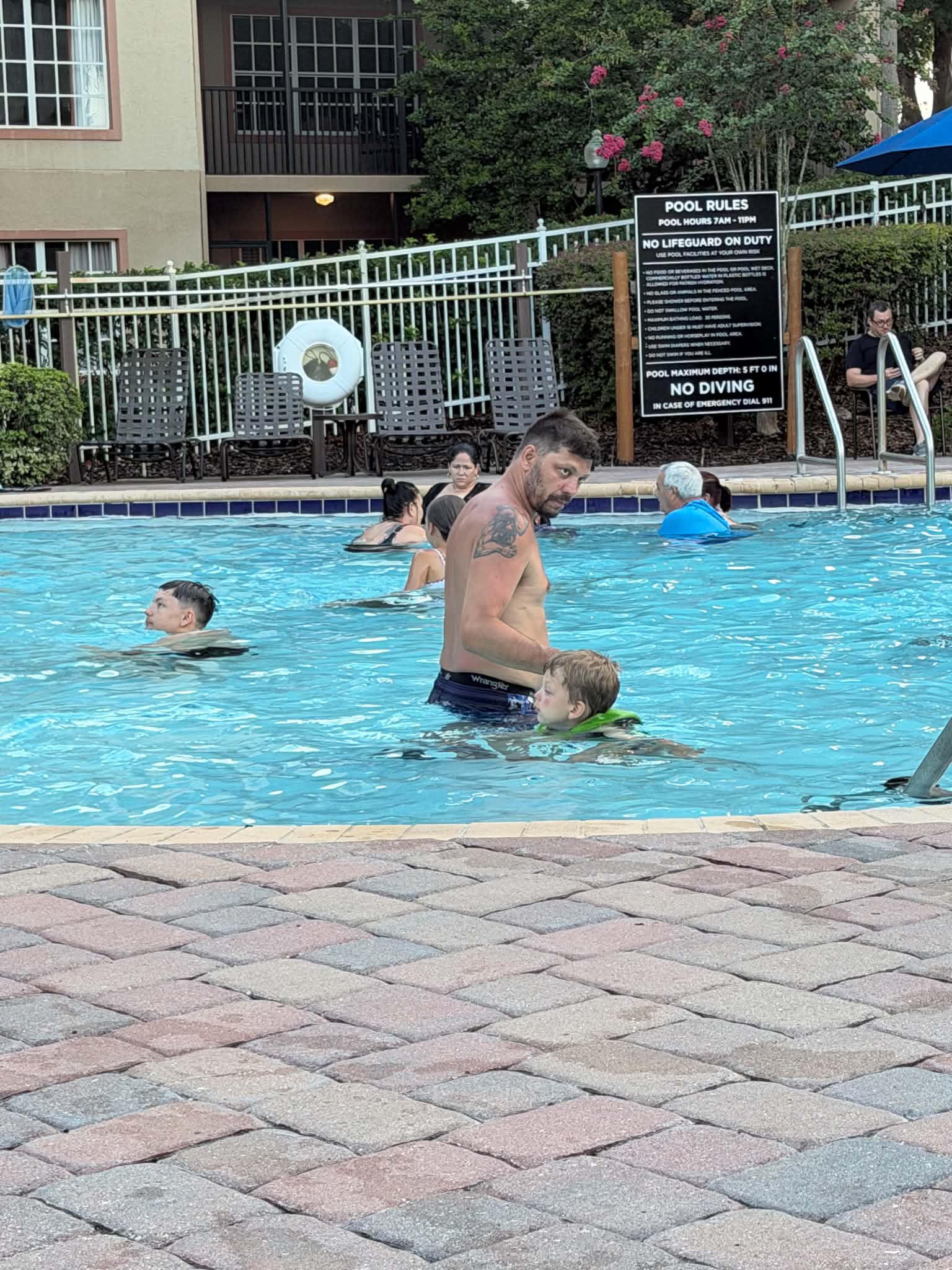 Guests swim in the main Hilton Aqua Sol pool with resort balconies and flowering bushes visible behind them