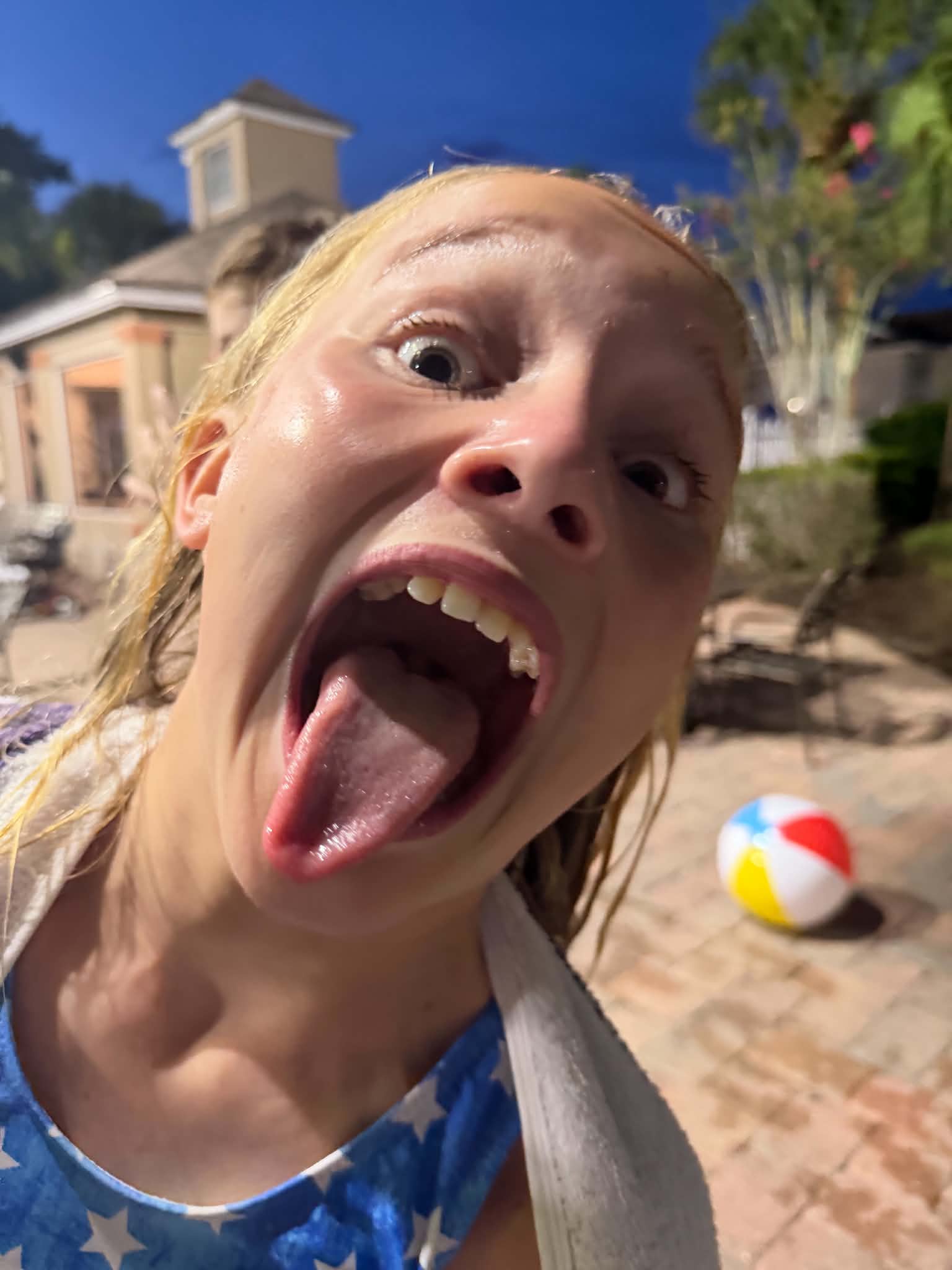 A girl makes a silly face during a nighttime poolside gathering at the resort