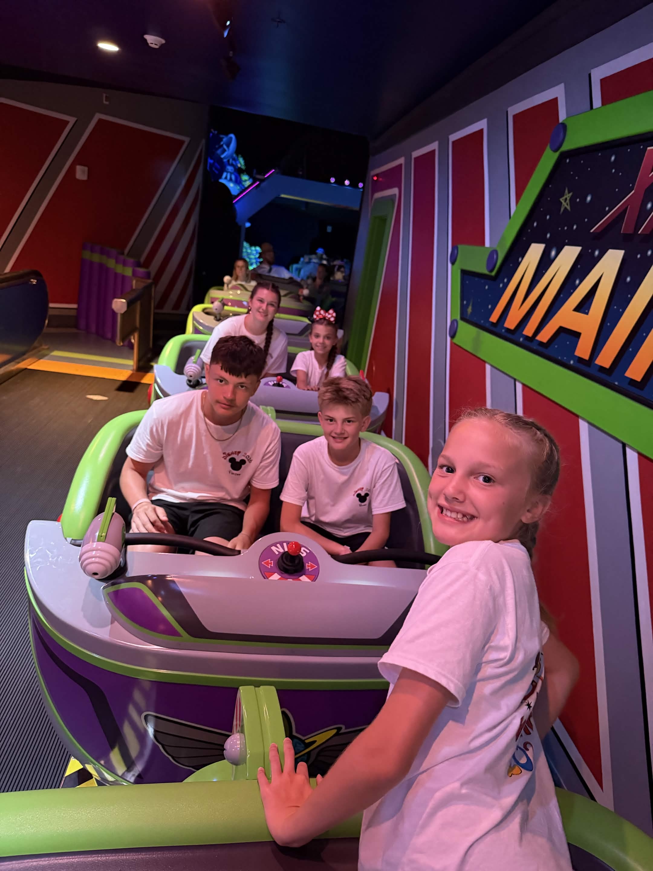 Kids in matching Disney shirts riding the Buzz Lightyear Space Ranger Spin