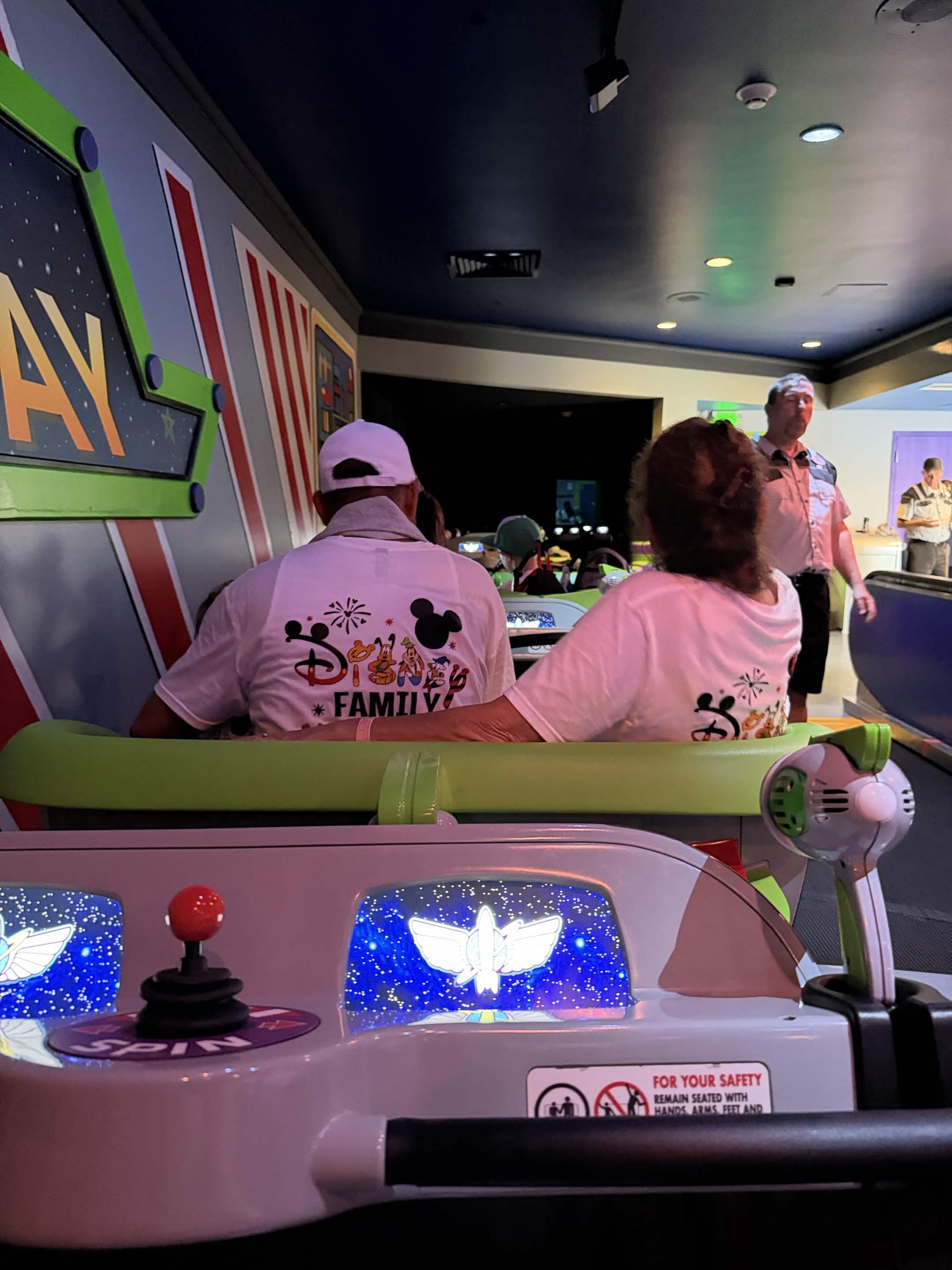 Adults in matching Disney Family shirts on Buzz Lightyear ride loading area