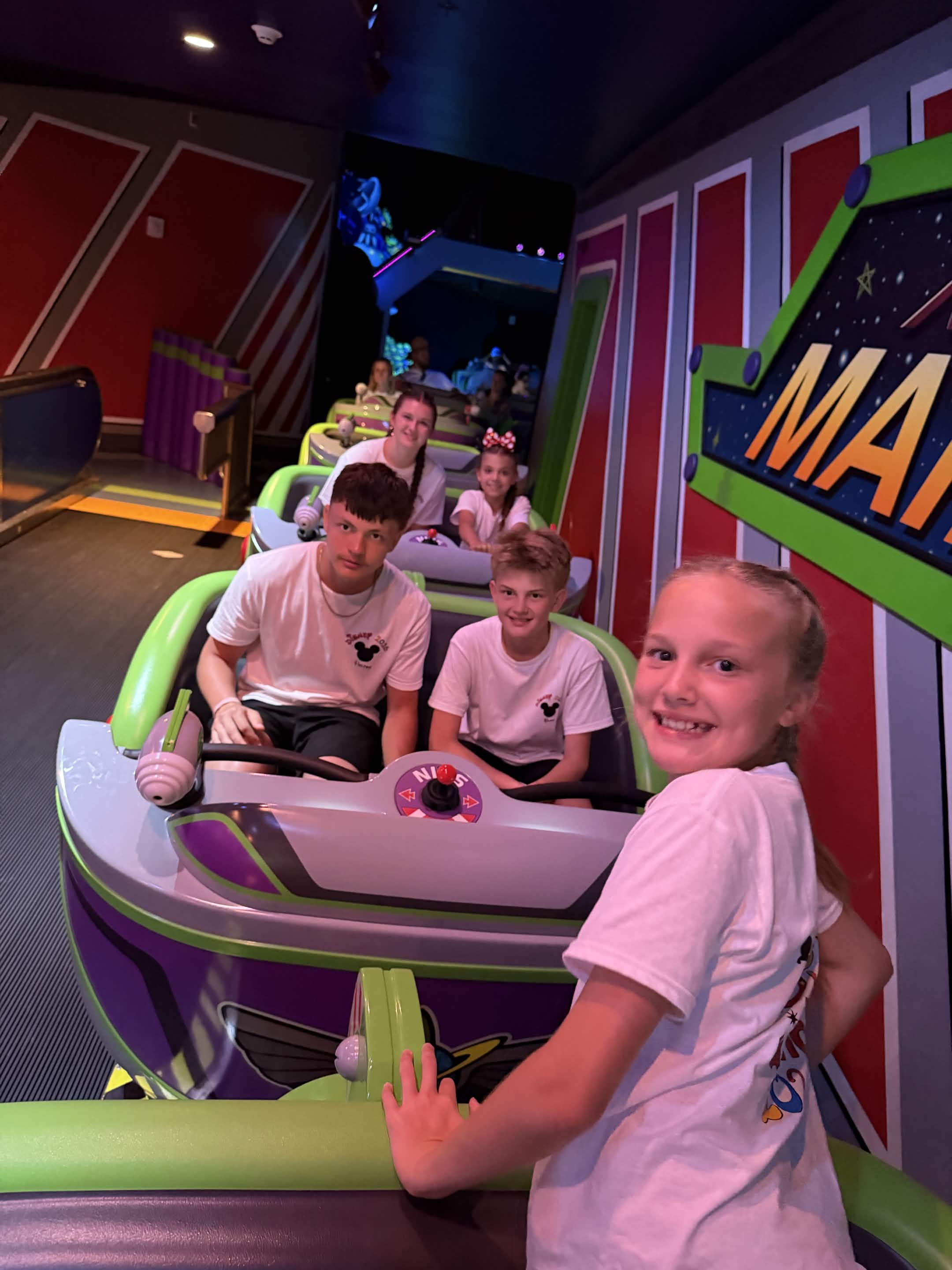 Close-up of kids in Buzz Lightyear ride vehicles with laser blaster controls