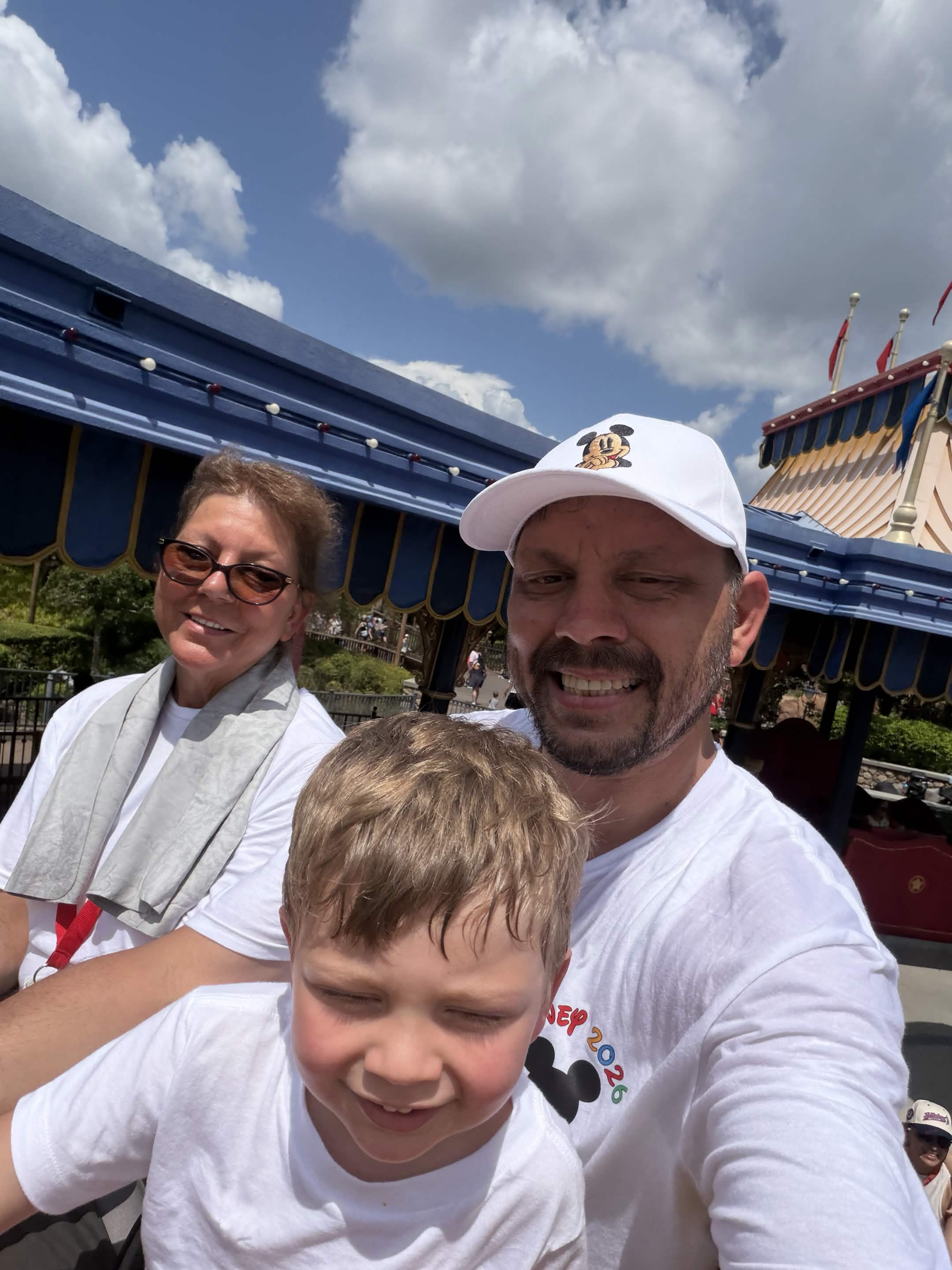 Family selfie near Dumbo area with circus tent flags in the background
