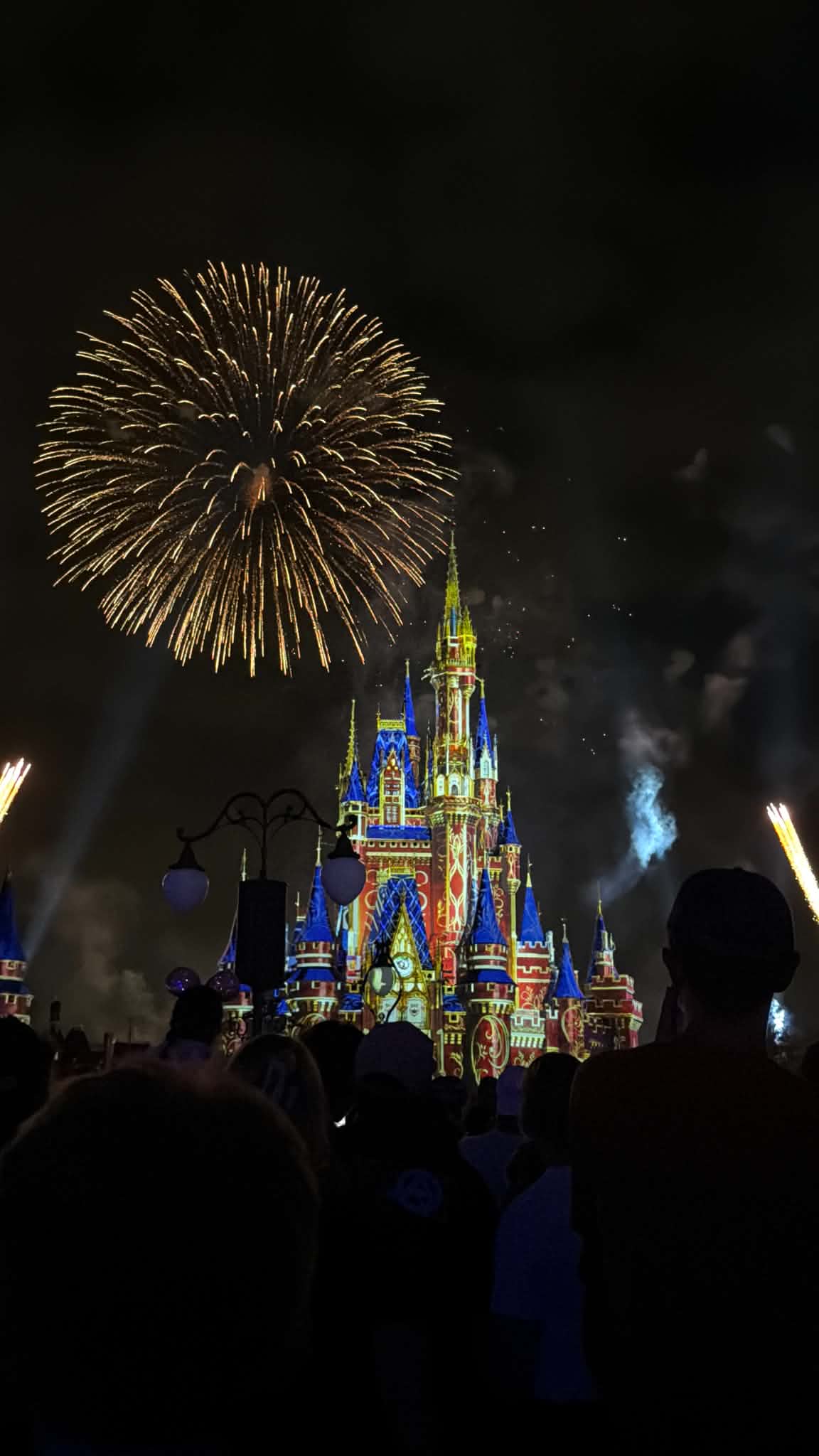 Close view of fireworks over Cinderella Castle with Mickey-ear silhouettes in the foreground