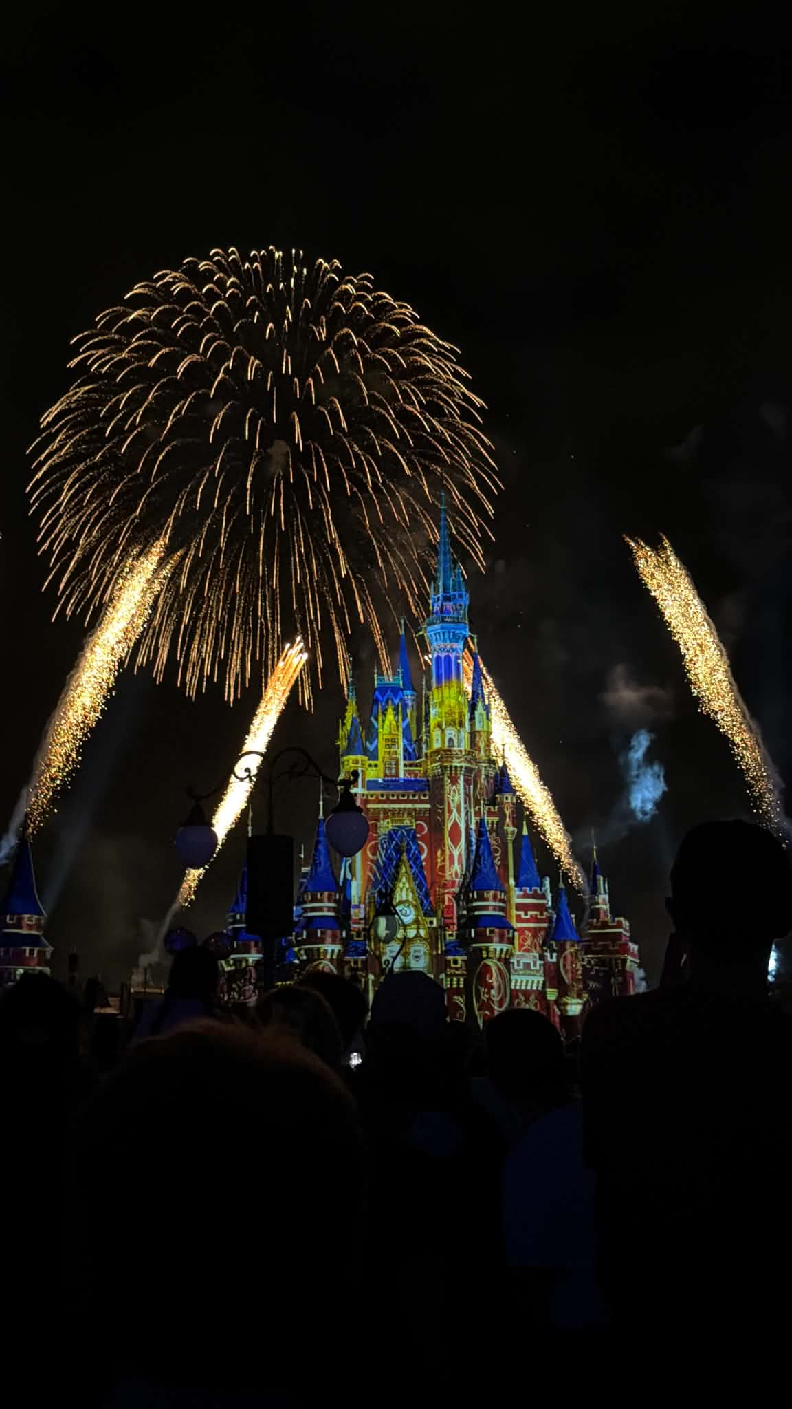 Fireworks arcing from both sides of Cinderella Castle with colorful projections