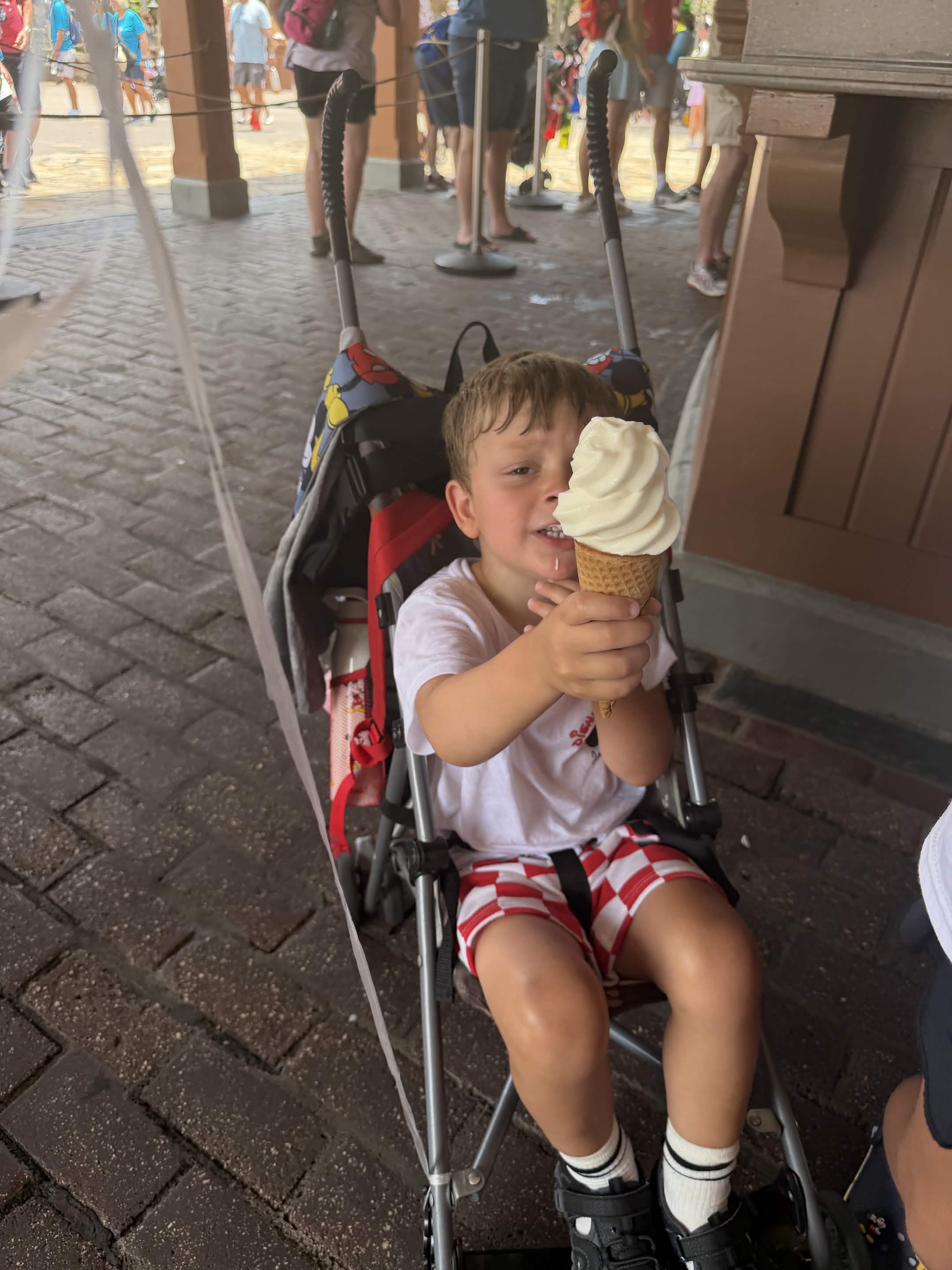Young child in a stroller holding a vanilla soft-serve ice cream cone at Magic Kingdom