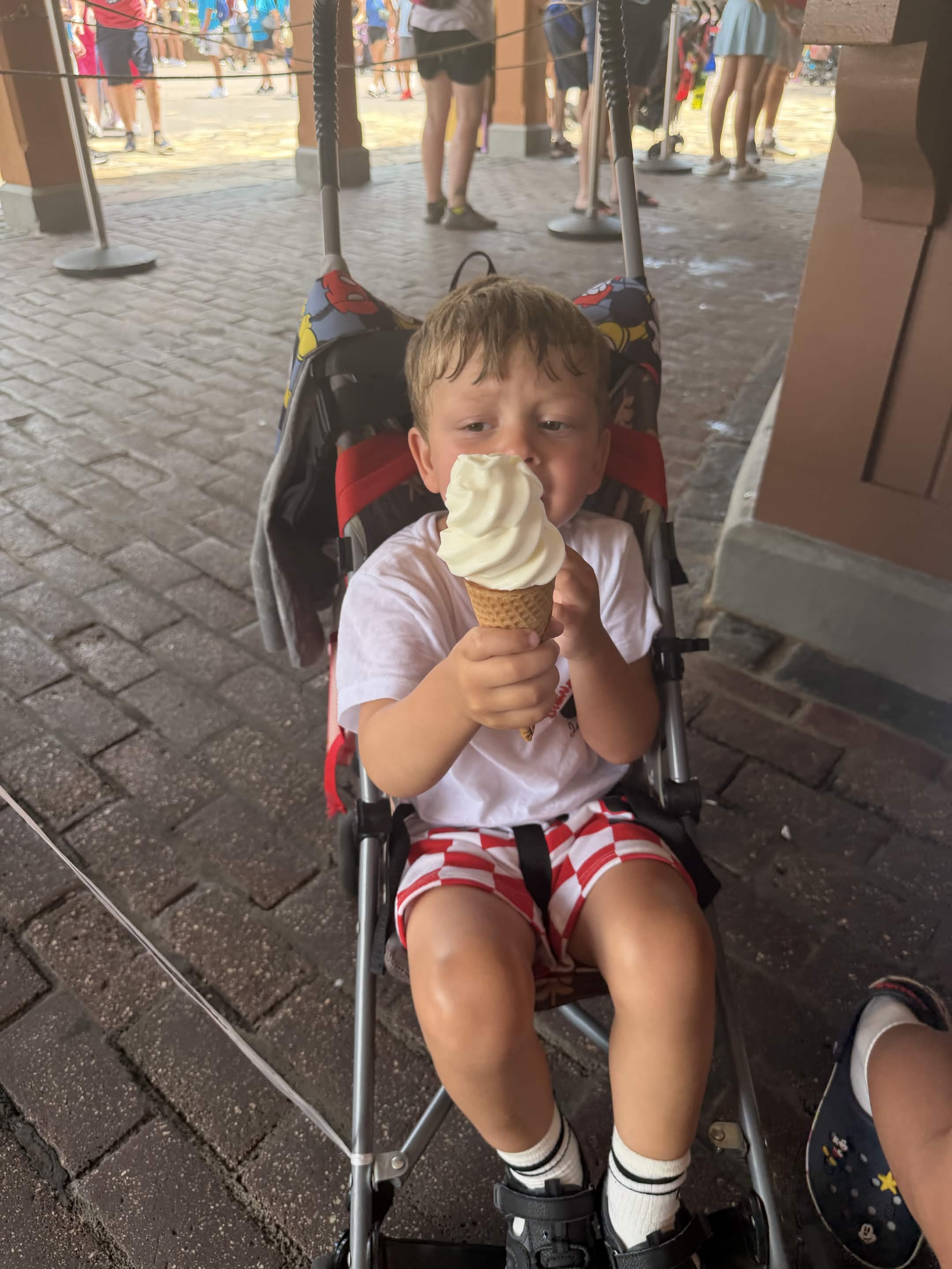 Close-up of child eating vanilla ice cream cone in stroller
