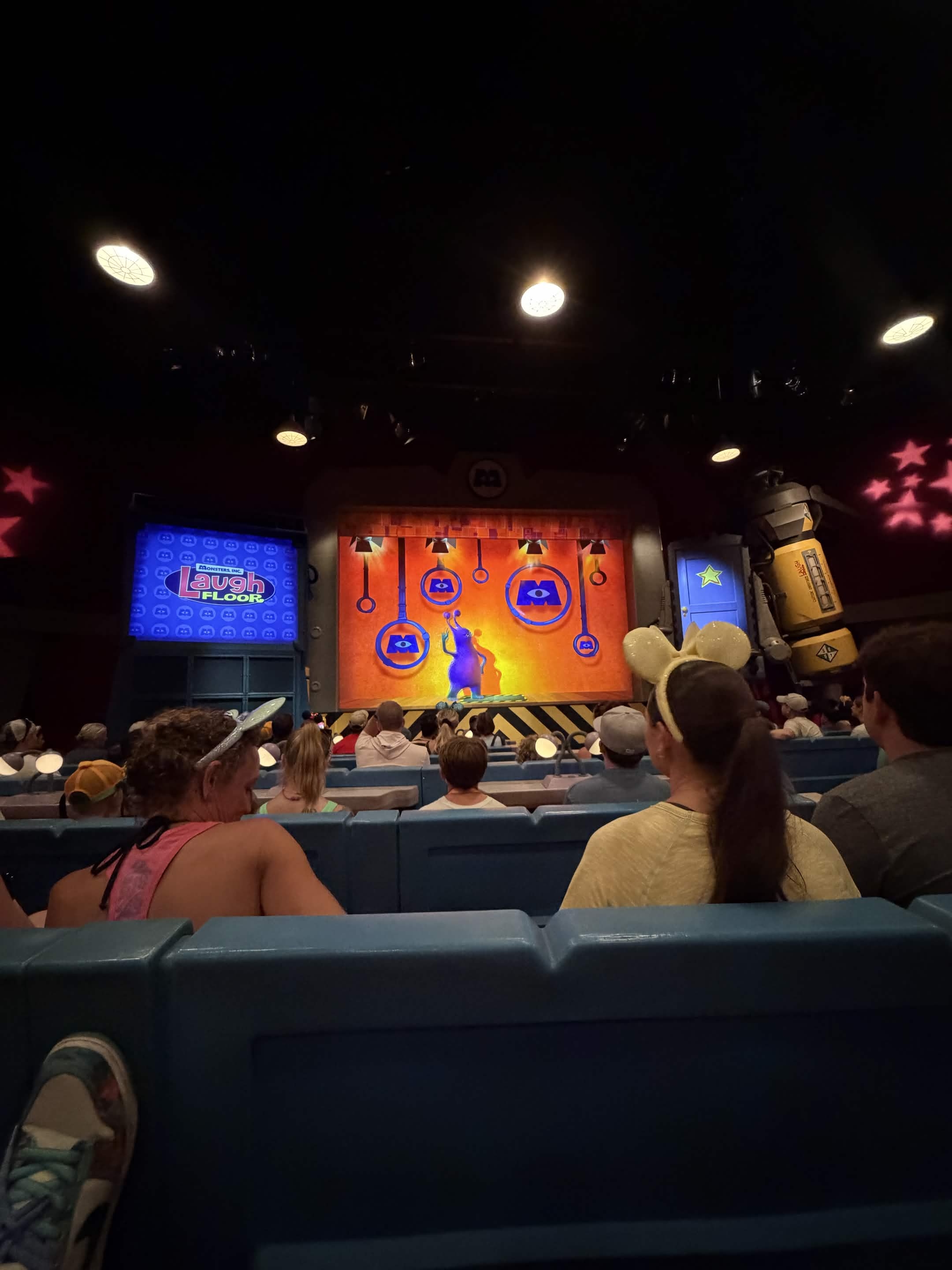 Inside the Monsters Inc Laugh Floor theater with the show on screen