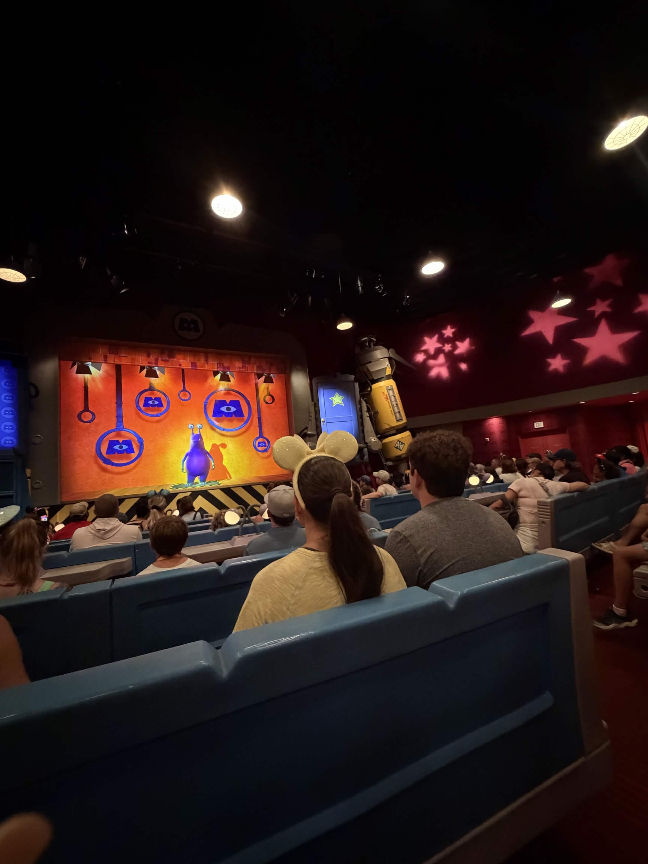 Laugh Floor audience with guest in sparkly Mickey ears watching the show
