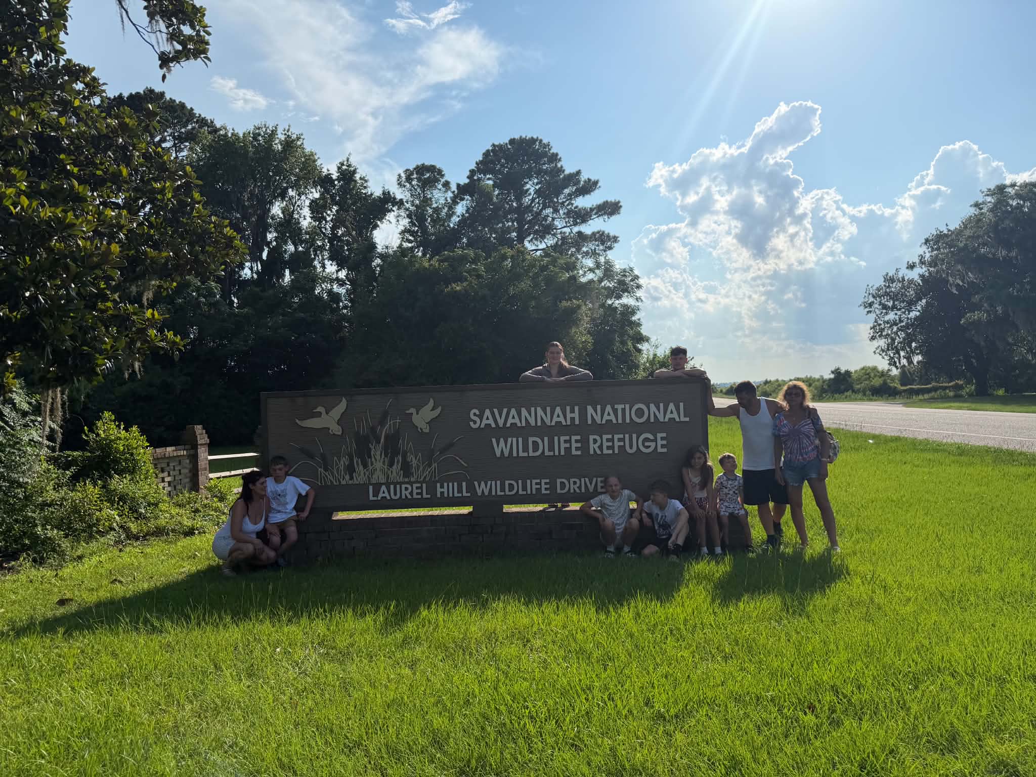 Backlit group photo at the refuge entrance sign with dramatic sunbeams