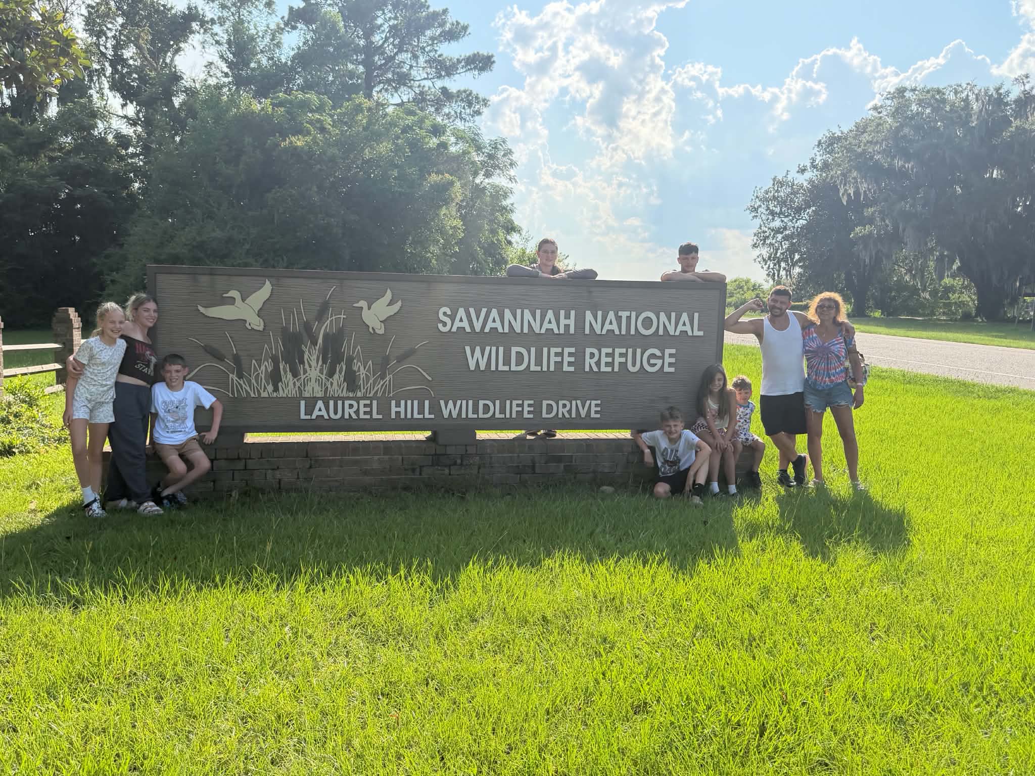 Family arranged around the refuge sign with kids sitting at the base