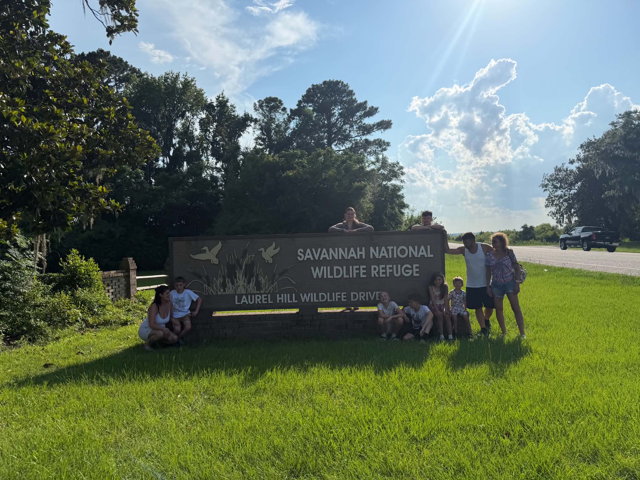 Wide shot of the group at the refuge entrance sign with sun rays